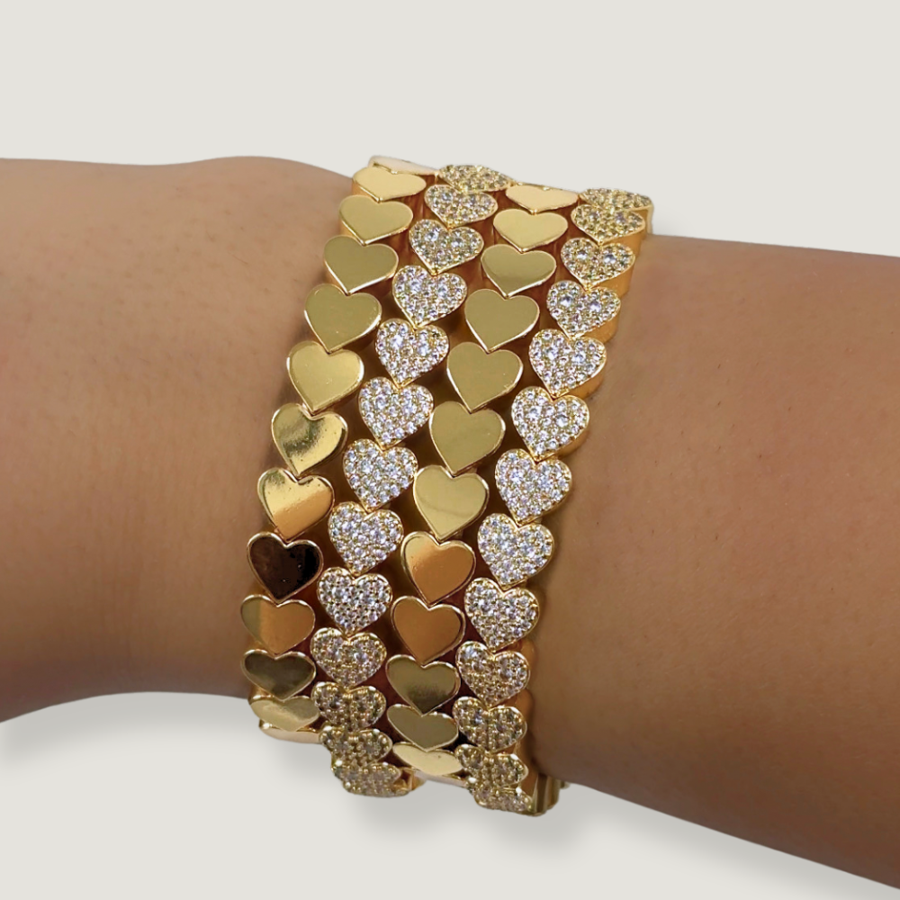 Gold and silver heart-shaped bracelet on a wrist against a white background