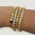 Gold and silver heart-shaped bracelet on a wrist against a white background