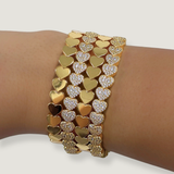 Gold and silver heart-shaped bracelet on a wrist against a white background