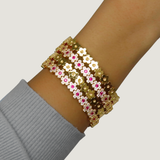 Gold bracelet with pink gemstones on a wrist against a neutral background